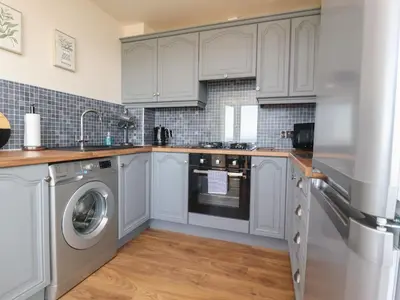 a kitchen with white cabinets and a washer and dryer at Flat 3, Sandridge Court in Fleetwood