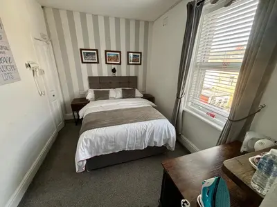 a bedroom with a bed and a table and a window at Lee & Chris's Belvedere - Adults Only in Blackpool