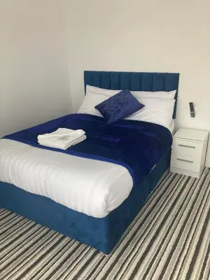 a bed with blue and white sheets and pillows at The New Astoria Hotel in Blackpool