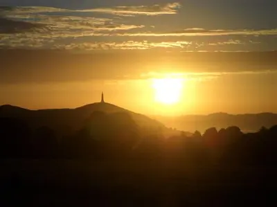 a sunset over a hill with a lighthouse on top at 4 bedroom house, central Ulverston in Ulverston