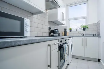 a white kitchen with a microwave and a sink at Beautiful apartment dos - free public parking in Litherland