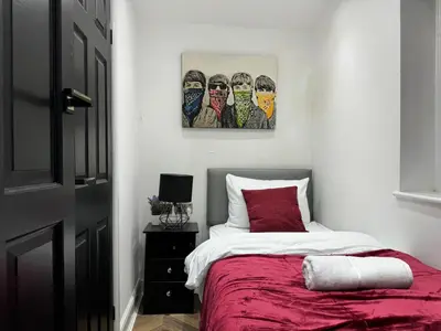 a bedroom with a bed and a painting on the wall at 4 bed 4 bath House with Free Parking, 5 Mins to LFC and 15 Mins to City Centre in Liverpool