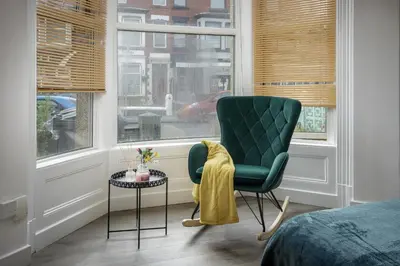a bedroom with a green chair and a table and a window at Seaside Suite 1 - Great Location Perfect For Long Stays in Blackpool