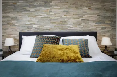 a bed with two pillows and a brick wall at Seaside Suite 1 - Great Location Perfect For Long Stays in Blackpool