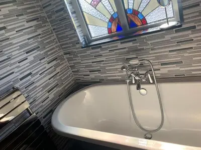 a bath tub in a bathroom with a stained glass window at Family Holiday Home in Blackpool