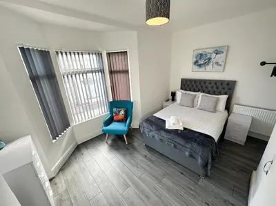 a bedroom with a bed and a blue chair at Vicar Road in Liverpool