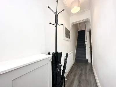 a hallway with white walls and a staircase with black umbrellas at Vicar Road in Liverpool