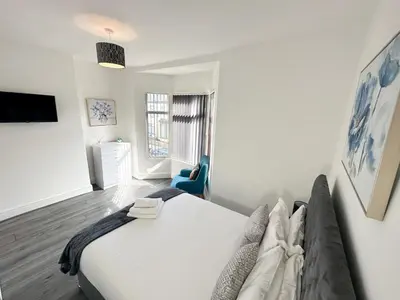 a bedroom with a large bed and a blue chair at Vicar Road in Liverpool