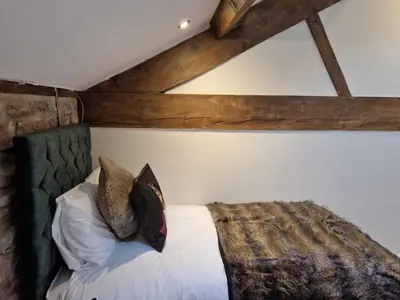 a bedroom with a bed with a green headboard and pillows at 8 Coach House in Preston