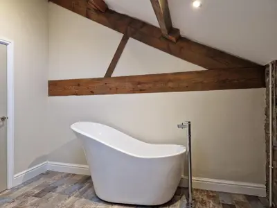 a white bath tub in a bathroom with wooden ceilings at 8 Coach House in Preston