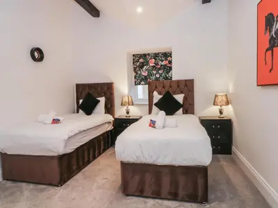 two beds in a room with two lamps at 7 Holly Barn in Preston