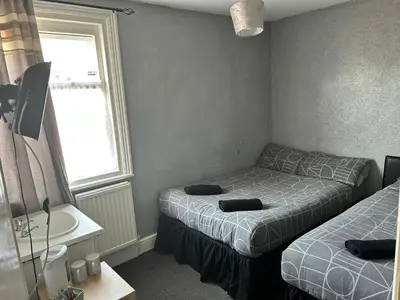 a bedroom with two beds and a sink and a window at Adina Hotel in Blackpool