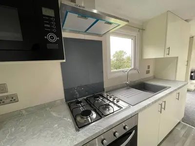 a kitchen with a stove and a sink and a window at 136, Port Haverigg in Millom