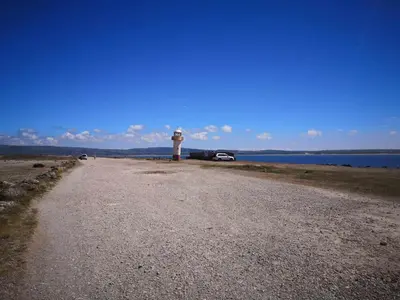 a lighthouse on a gravel road next to a body of water at 136, Port Haverigg in Millom