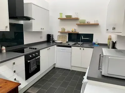a kitchen with white cabinets and black appliances at Newly renovated 4 bedroom house in Ulverston in Ulverston