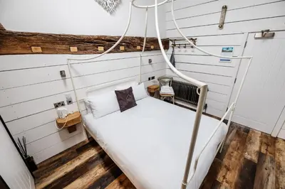 a bed in a room with white walls at Bashall Barn in Clitheroe