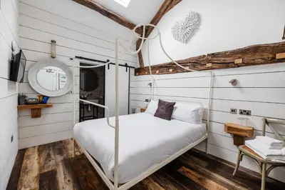 a bed in a room with white walls and wood floors at Bashall Barn in Clitheroe