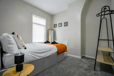 a bedroom with a bed and a cross on the wall at Stay with Alexandra - Free Parking - Free Wifi Superb Location in Liverpool
