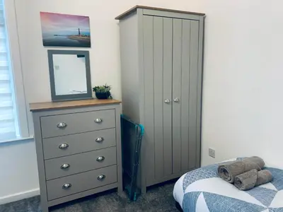 a bedroom with a bed and a dresser with a mirror at The WhiteHouse Holiday Apartments in Blackpool