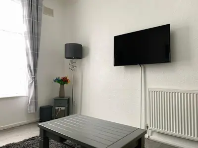 a living room with a flat screen tv on a wall at The WhiteHouse Holiday Apartments in Blackpool