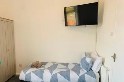 a bedroom with a bed and a television on the wall at The WhiteHouse Holiday Apartments in Blackpool