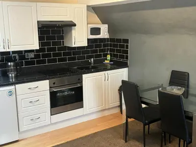 a kitchen with white cabinets and a table with chairs at Phillips Apartments in Blackpool