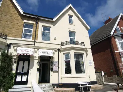 a white house with a bench in front of it at Phillips Apartments in Blackpool