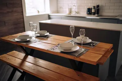 a wooden table with plates and wine glasses on it at The Windmill, Lytham St Annes in Saint Annes on the Sea