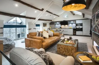 a living room with brown furniture and a kitchen at Wharton House Mews in Cartmel, Lake District - Ridgestone in Cartmel