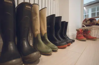 a row of boots are lined up against a wall at Wharton House Mews in Cartmel, Lake District - Ridgestone in Cartmel