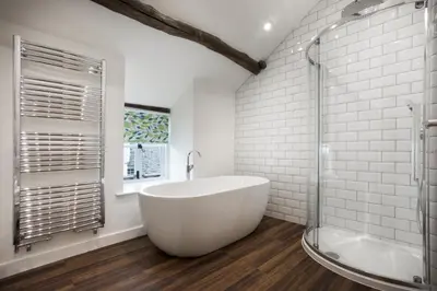 a white bathroom with a tub and a window at Wharton House Mews in Cartmel, Lake District - Ridgestone in Cartmel