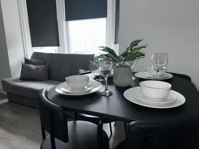 a black table with plates and glasses and a couch at New osborne hot tub and jacuzzi suites in Blackpool