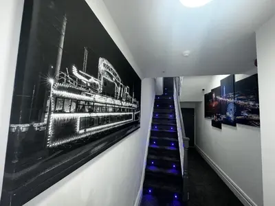 a hallway with a staircase with paintings on the wall at New osborne hot tub and jacuzzi suites in Blackpool