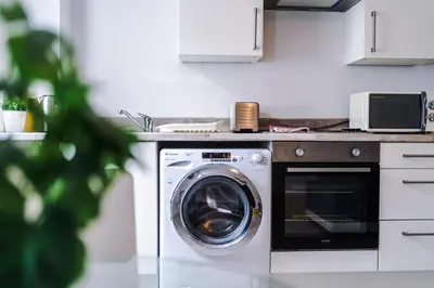 a washing machine in a kitchen next to a counter at 1BR & 2BR Apt -for CONTRACTORS- free PARKING close to EVERTON & ANFIELD stadium, Liverpool City Centre managed by Chique Properties Ltd in Liverpool