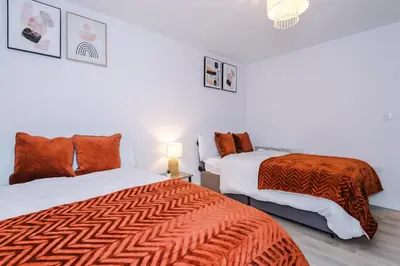 a bedroom with two beds with orange and white sheets at 1BR & 2BR Apt -for CONTRACTORS- free PARKING close to EVERTON & ANFIELD stadium, Liverpool City Centre managed by Chique Properties Ltd in Liverpool