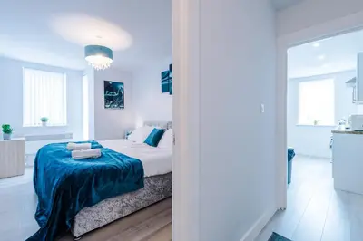 a white bedroom with a bed with a blue blanket at 1BR & 2BR Apt -for CONTRACTORS- free PARKING close to EVERTON & ANFIELD stadium, Liverpool City Centre managed by Chique Properties Ltd in Liverpool