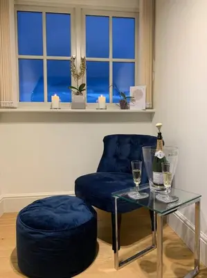 a living room with a blue chair and a glass table at Stunning 3 Bedroom Penthouse in Ulverston Center in Ulverston