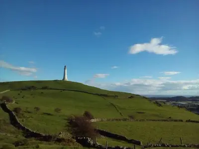 a green hill with a monument on top of it at Stunning 3 Bedroom Penthouse in Ulverston Center in Ulverston