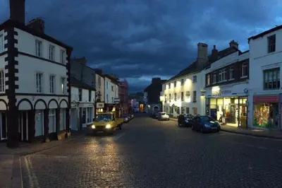 a city street at night with cars driving down the street at Stunning 3 Bedroom Penthouse in Ulverston Center in Ulverston