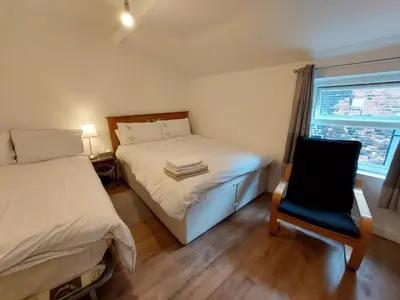 a bedroom with two beds and a chair and a window at Liverpool Newington Stay in Liverpool