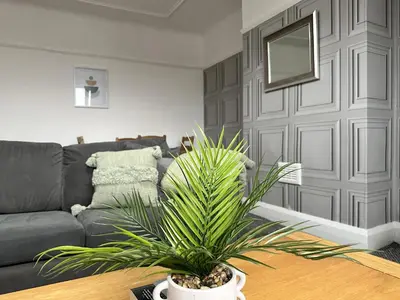 a living room with a couch and a plant on a table at Charming Apartment Near Broad Green Hospital in Liverpool