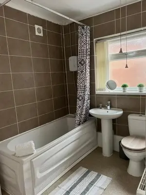 a bathroom with a tub and a toilet and a sink at Charming Apartment Near Broad Green Hospital in Liverpool