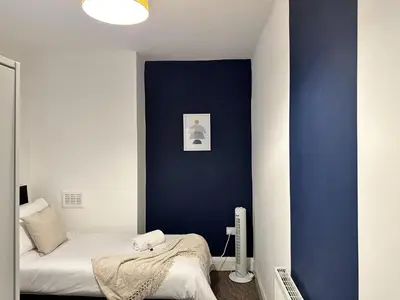 a bedroom with a blue accent wall and a bed at Charming Apartment Near Broad Green Hospital in Liverpool