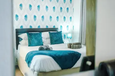a bedroom with a large bed with blue pillows at Blackpool Lodge in Blackpool