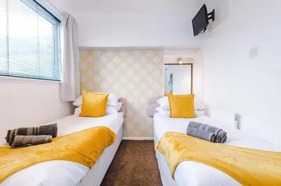 two beds in a room with yellow pillows at Blackpool Lodge in Blackpool