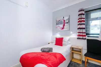 a small bedroom with a red bed and a chair at Blackpool Lodge in Blackpool