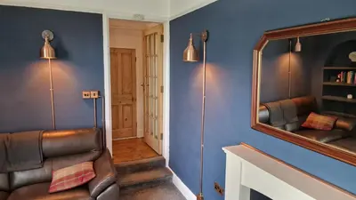 a hallway with a mirror and a leather chair at Carr Garth in Arnside