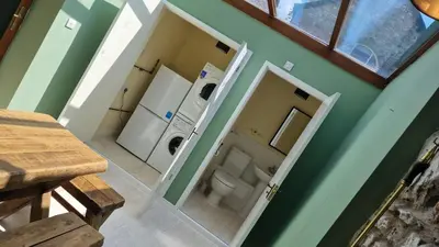 a small bathroom with a toilet and a laundry room at Carr Garth in Arnside
