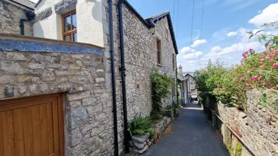 a stone building with a wooden door on a street at Carr Garth in Arnside