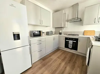 a white kitchen with white appliances and wooden floors at Entire house, Waterloo, free street parking in Waterloo